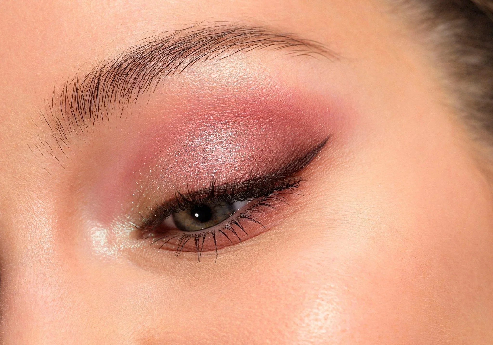 Gros plan sur œil maquillé avec fard à paupières rose et trait d'eyeliner noir pour un maquillage de jour