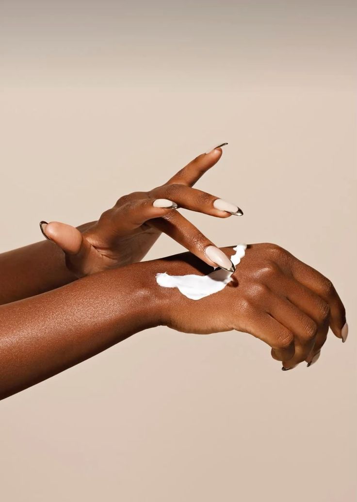 Mains de femme noire appliquant une crème hydratante blanche, soin peau douce et éclat