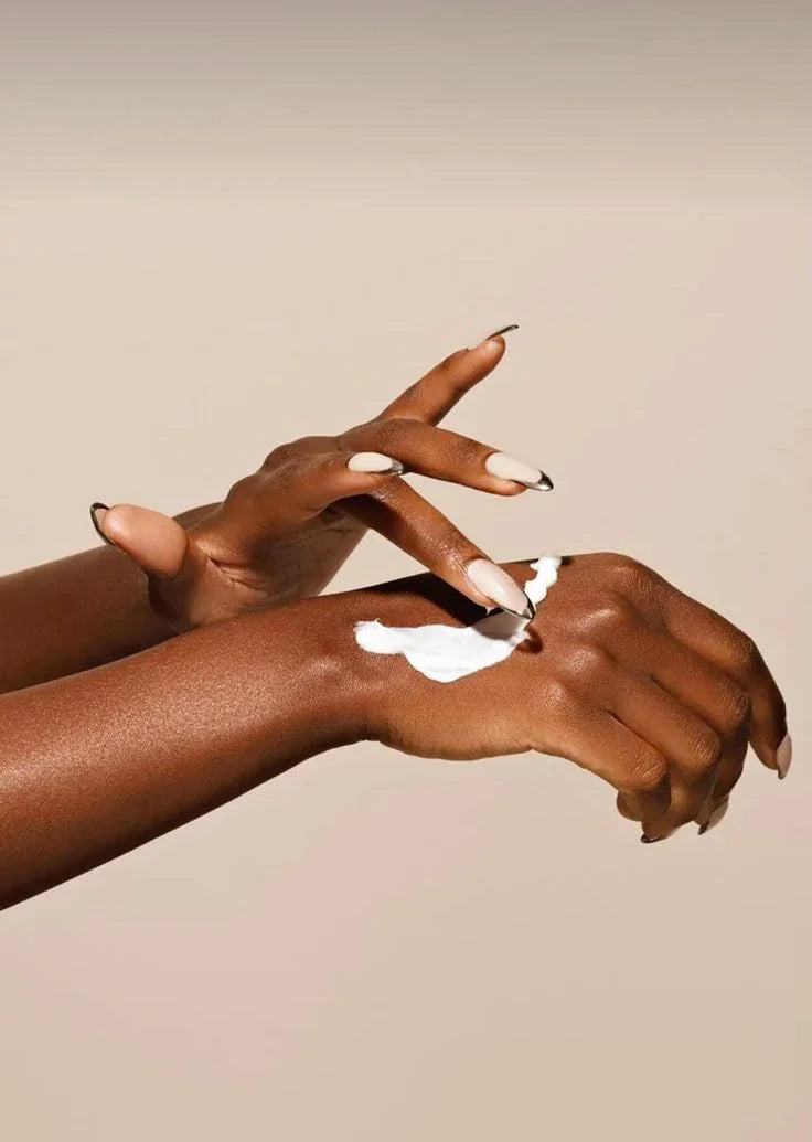 Mains de femme noire appliquant une crème hydratante blanche, soin peau douce et éclat