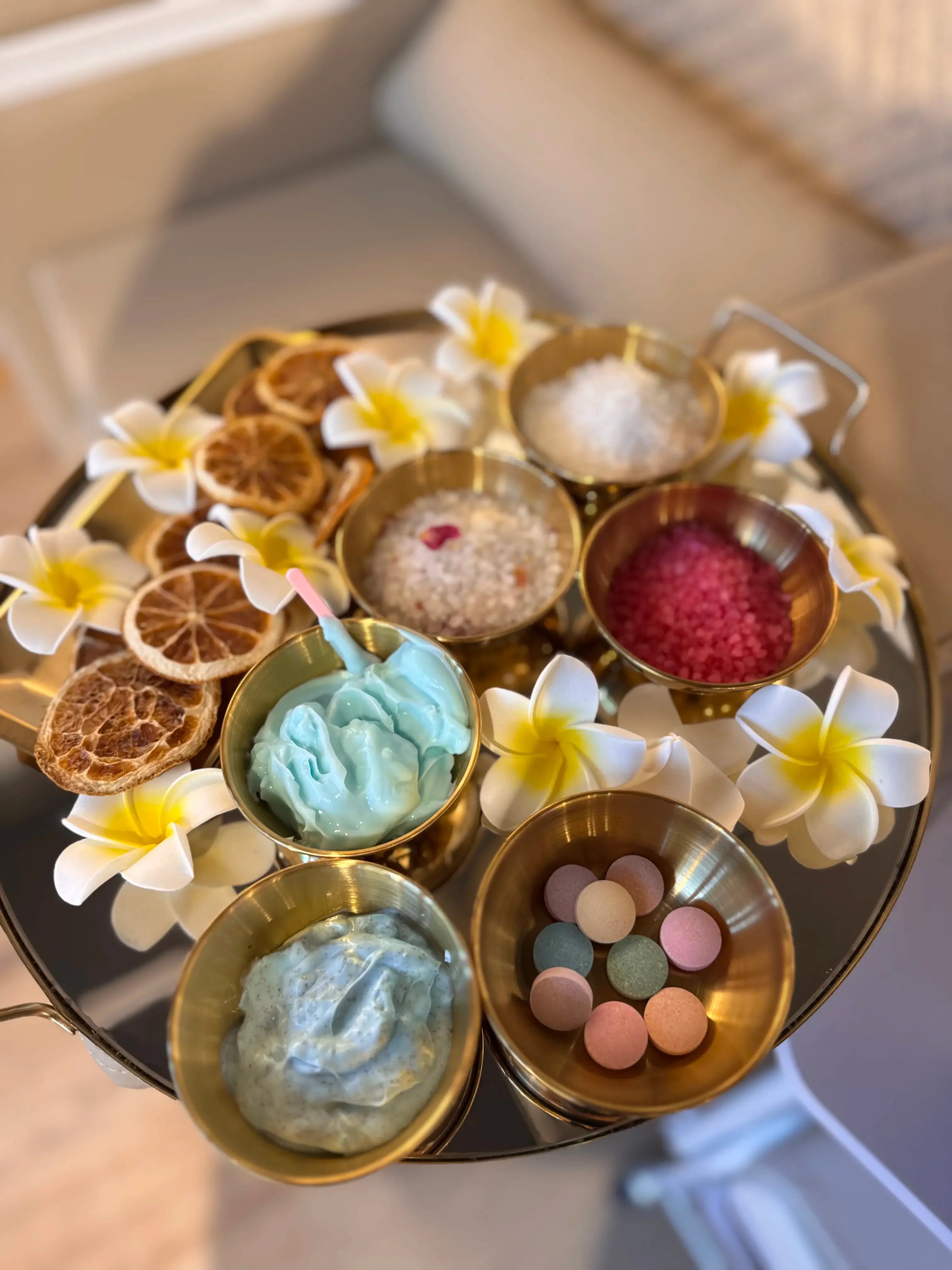 Plateau avec soins des pieds haut de gamme, crèmes bleues, sels de bain colorés, fleurs blanches jaunes, tranches d'agrumes séchées